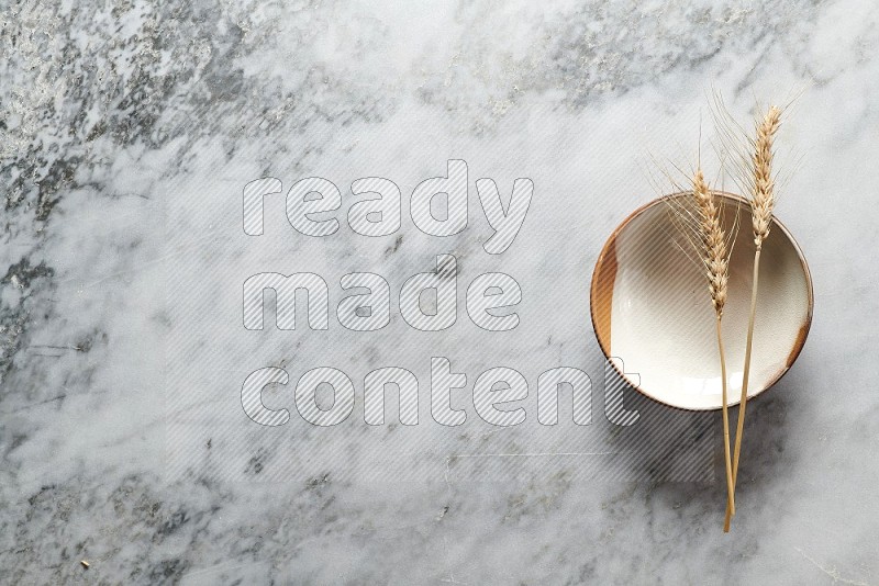 Wheat stalks on Multicolored Pottery Plate on grey marble flooring, Top view