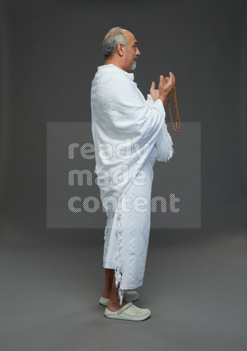 A man wearing Ehram Standing dua'a on gray background