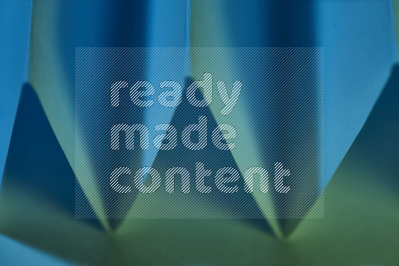 صورة مجردة مقربة تظهر طيات ورقية هندسية حادة بتدرجات اللون الأخضر والأزرق