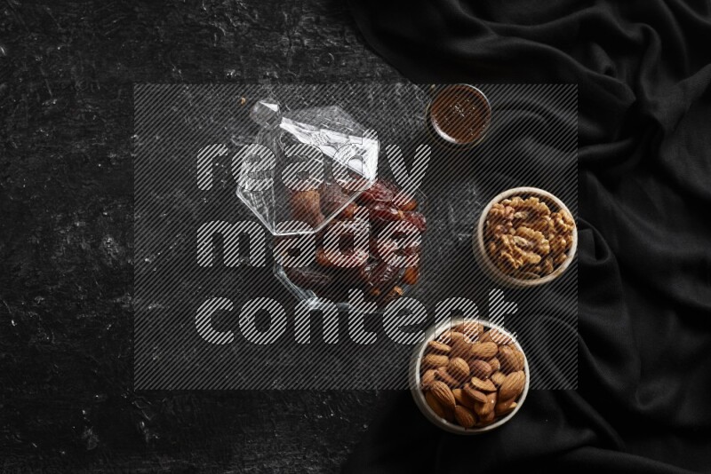 Dates in glass bowl with coffee and nuts in a dark setup
