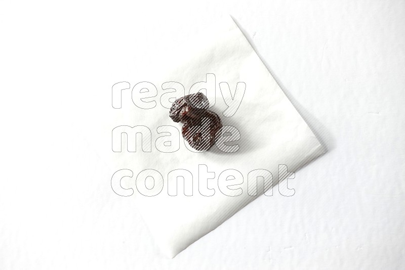 2 dried plums on a piece of paper on a white background in different angles