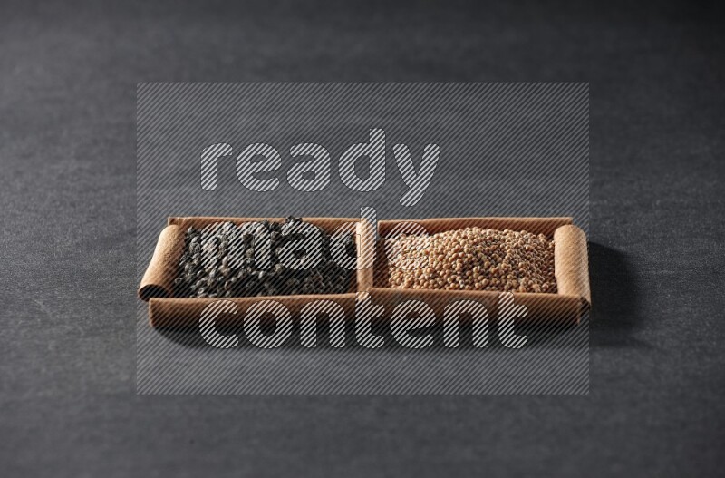 مربعان من أعواد القرفة ممتلئان بحبوب الخردل وحبوب الفلفل الأسود علي خلفية سوداء