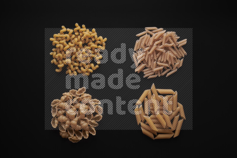 Different pasta types in bunches on black background