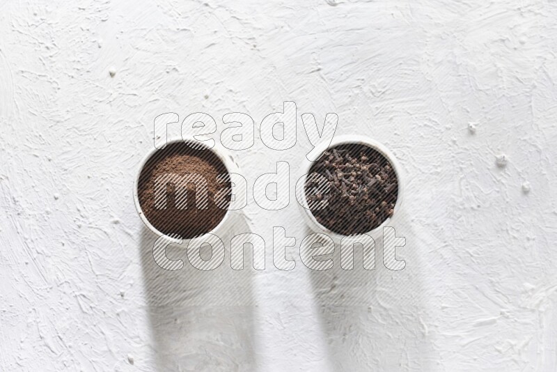 وعاءين من السيراميك بيج اللون، أحدهما مملوء بالقرنفل والآخر مملوء بالبودرة على أرضية بيضاء