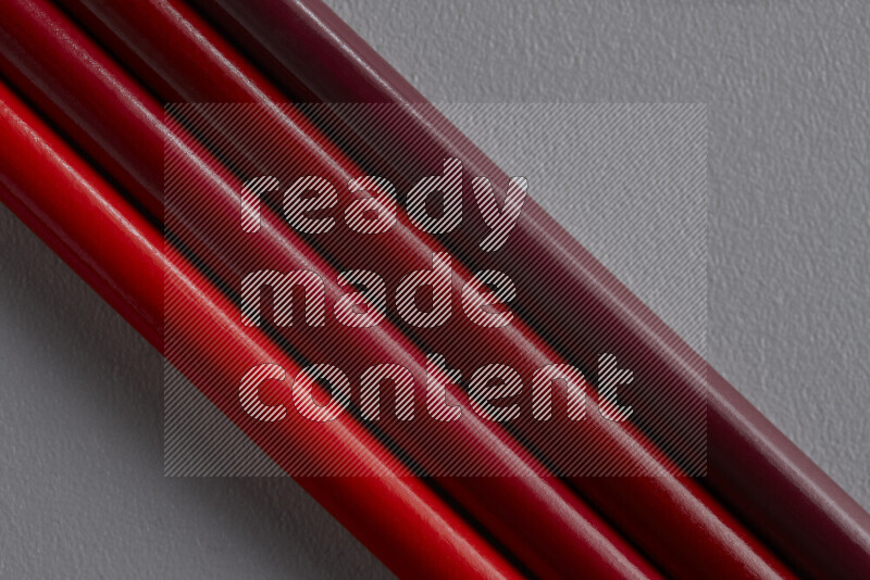 مجموعة من أقلام الرصاص الملونة مرتبة لتعرض تدرجا من الألوان الحمراء علي خلفية رمادية