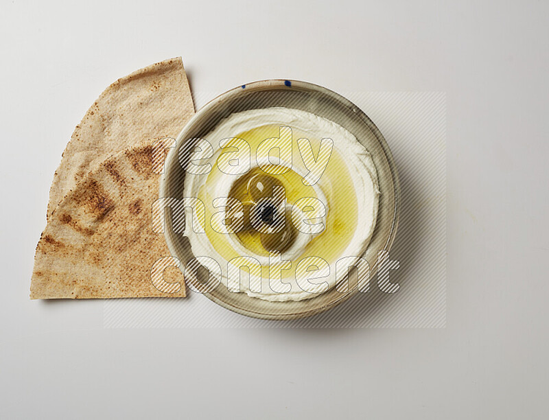 Lebnah garnished with whole olives in a grey pottery plate on a white background