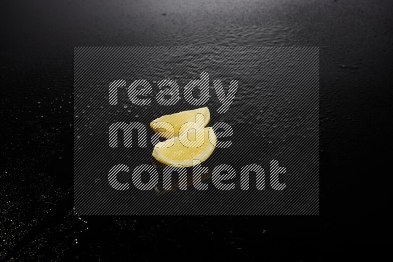 Lemon wedges with water drops, and droplets on black background