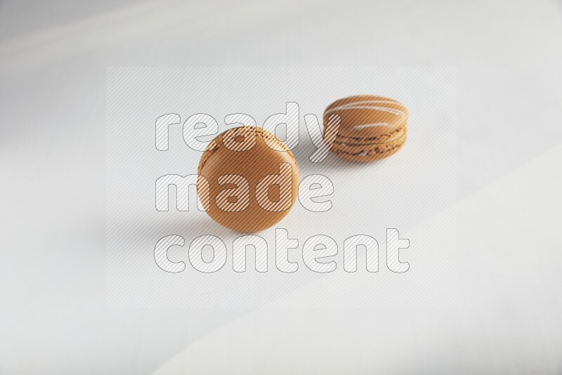 45º Shot of of two assorted Brown Irish Cream, and Brown Maple Taffy macarons  on white background