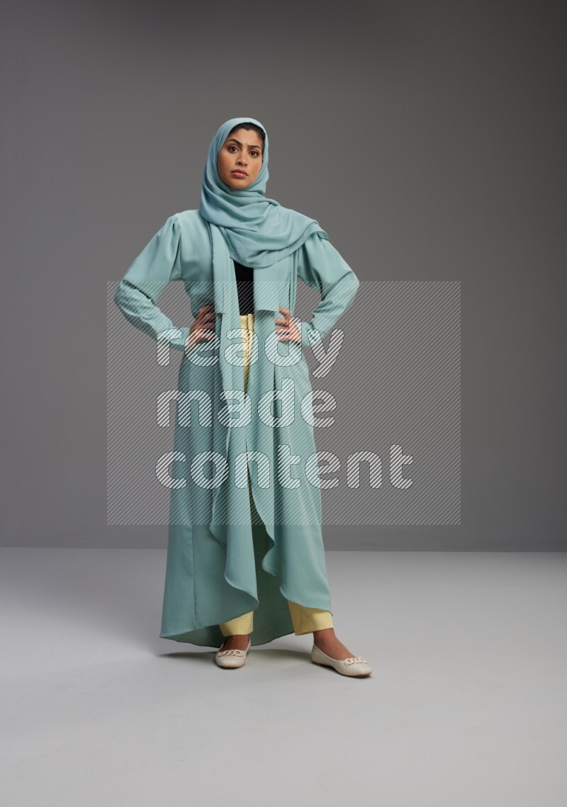 Saudi Woman wearing Abaya standing interacting with the camera on Gray background
