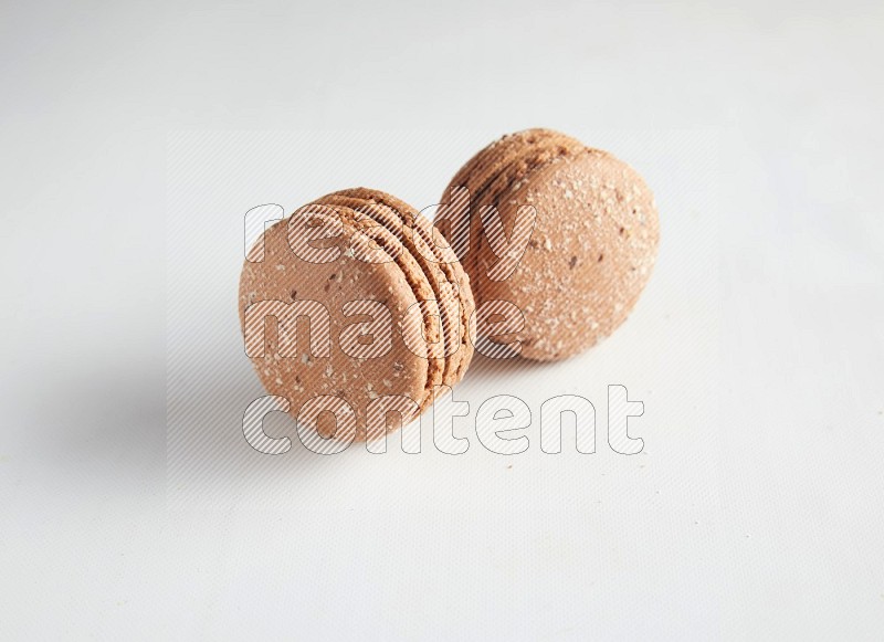 45º Shot of two Brown Hazelnuts macarons on white background