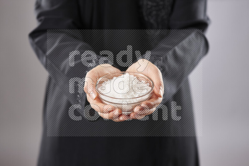 Woman in abaya holding different kinds of spices in different positions