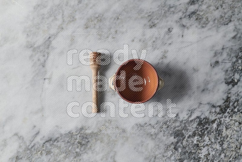 Brown Pottery Bowl with wooden honey handle on the side on grey marble flooring, Top view
