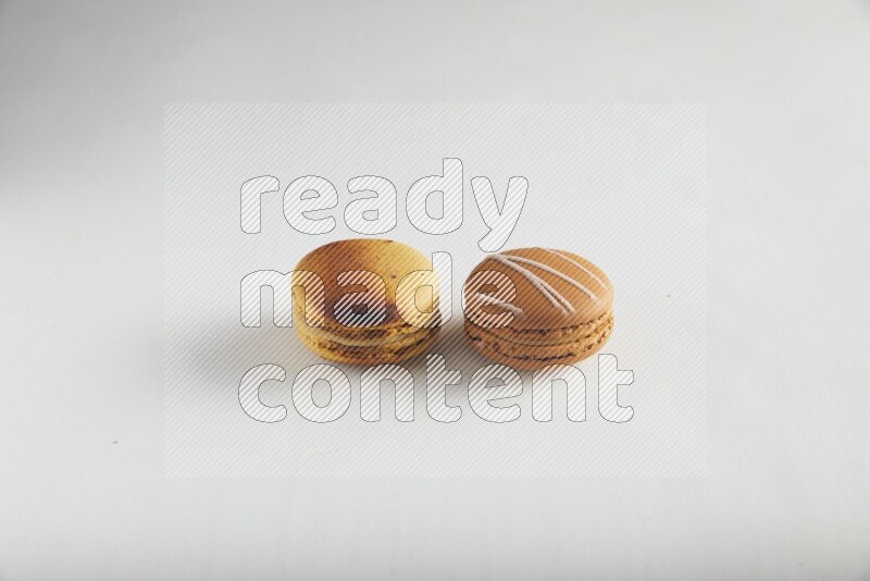 45º Shot of of two assorted Brown Irish Cream, and Yellow Crème Brulée macarons on white background