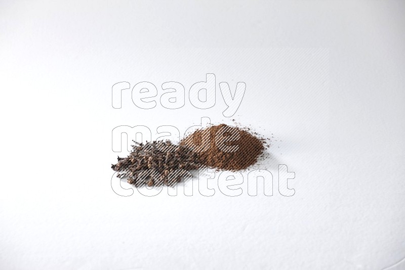 2 piles of cloves grains and cloves powder on a white flooring