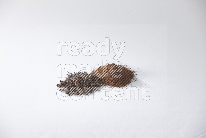 2 piles of cloves grains and cloves powder on a white flooring