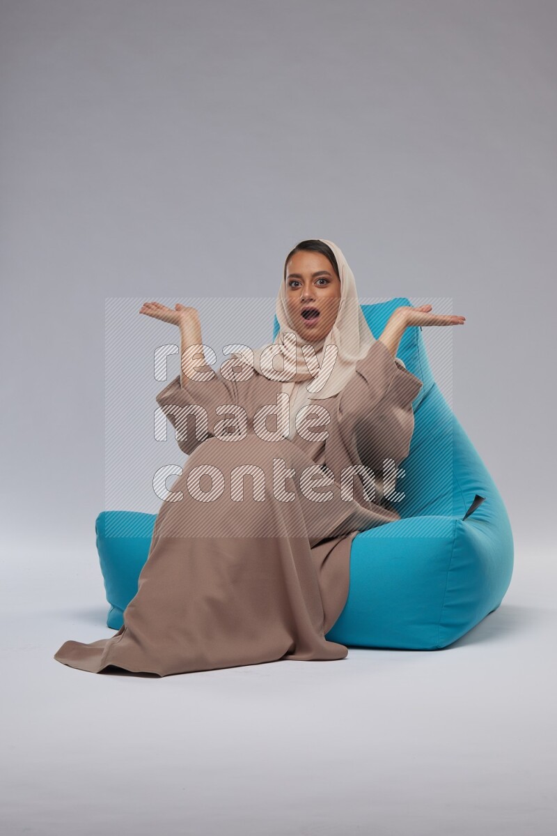 A woman sitting on a blue beanbag and interacting with the camera