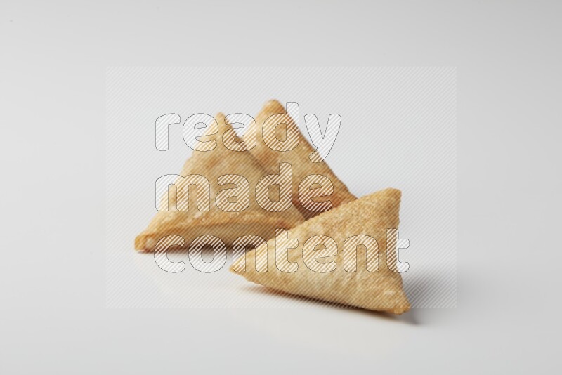 Three fried sambosas on a white background