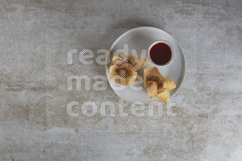 wonton cups with soy sauce ramkin on grey ceramic plate on grey textured counter top