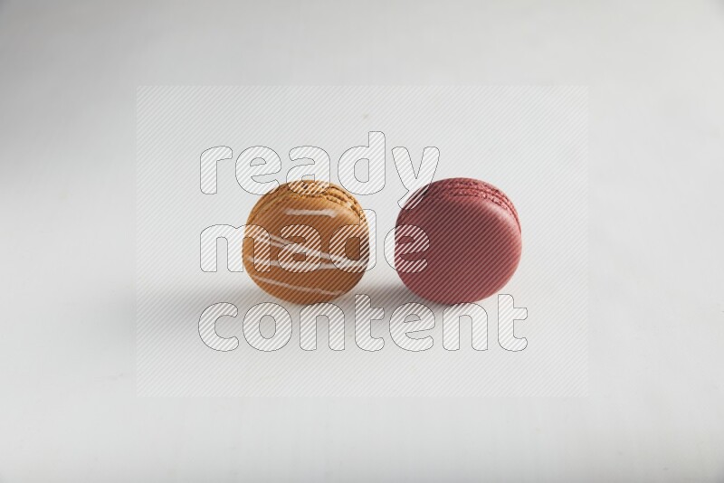 45º Shot of of two assorted Brown Irish Cream, and Red Velvet macarons on white background