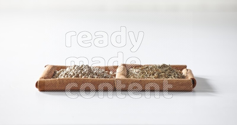 2 squares of cinnamon sticks full of white pepper and cumin on white flooring