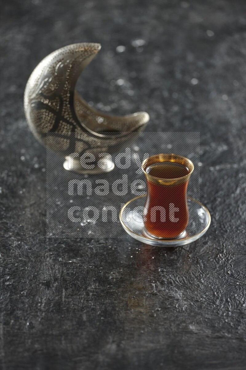 A silver lantern with different drinks, dates, nuts, prayer beads and quran on textured black background