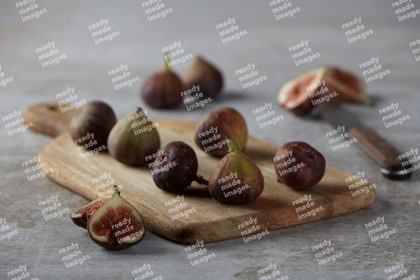 Fresh Figs on a wooden board on a textured grey background