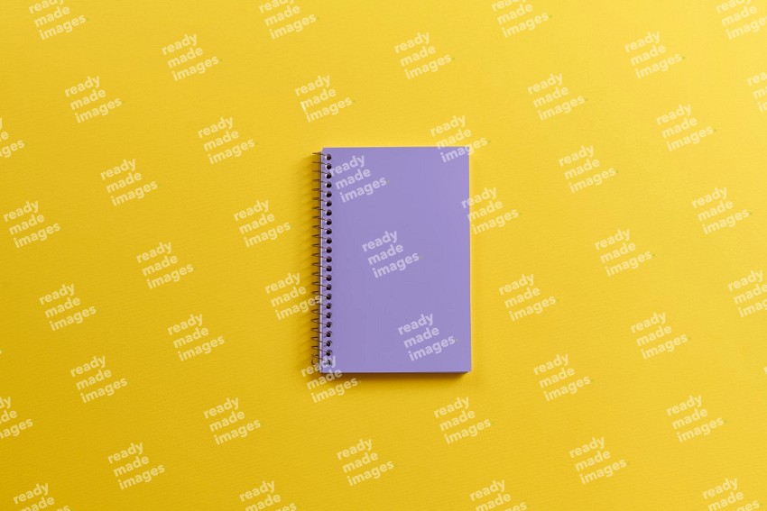 A purple notebook on yellow background (Back to school)