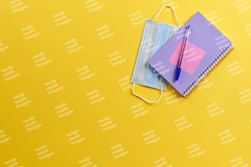 A purple notebook with school supplies on yellow background (Back to school)