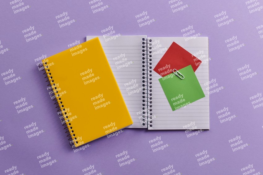 A yellow notebook with school supplies on purple background (Back to school)
