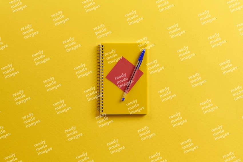 A yellow notebook with school supplies on yellow background (Back to school)