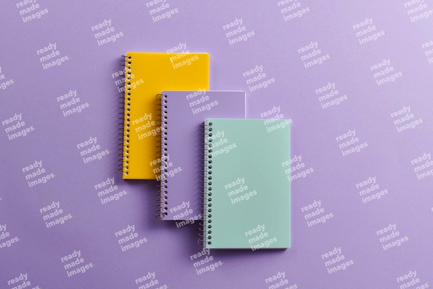 Multicolored notebooks on purple background (Back to school)