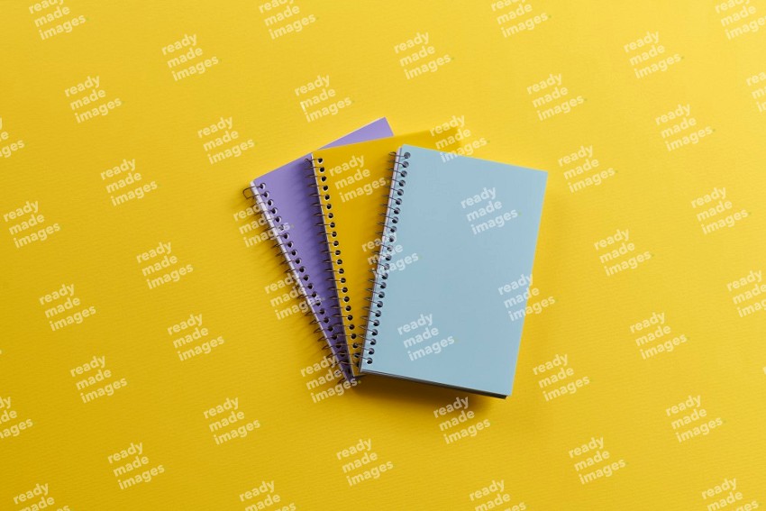 Multicolored notebooks on yellow background (Back to school)