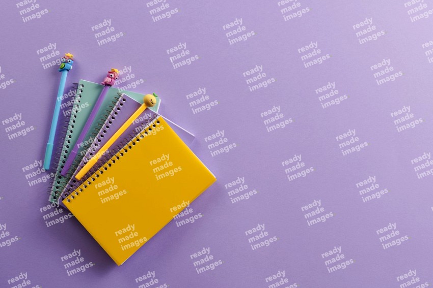 Multicolored notebooks with school supplies on purple background (Back to school)
