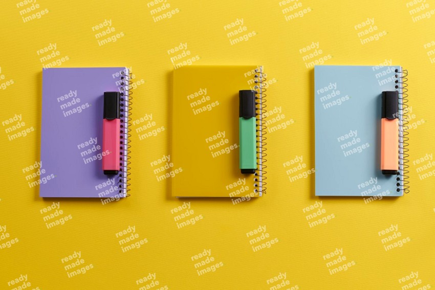 Multicolored notebooks with school supplies on yellow background (Back to school)
