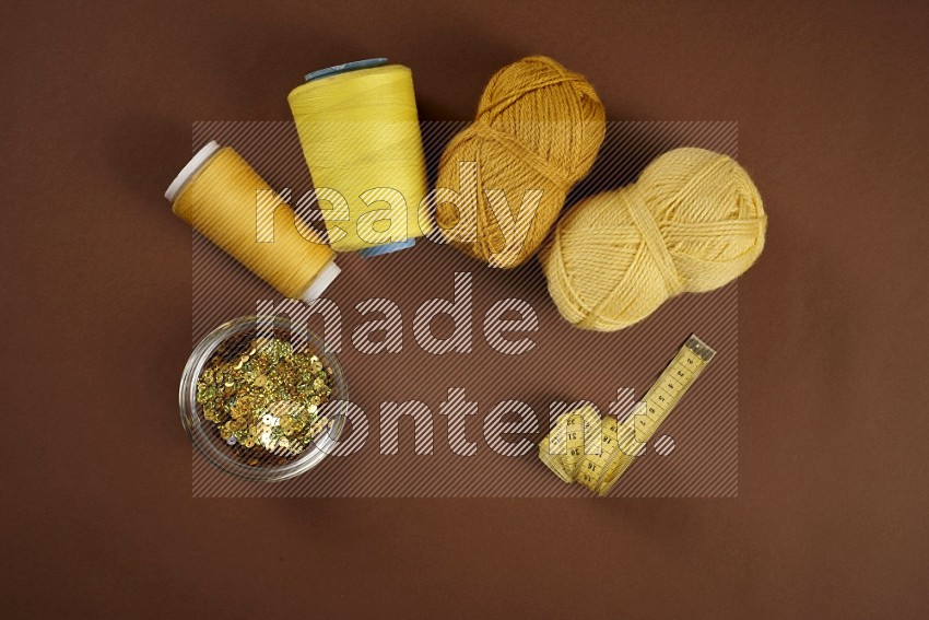 Yellow sewing supplies on brown background