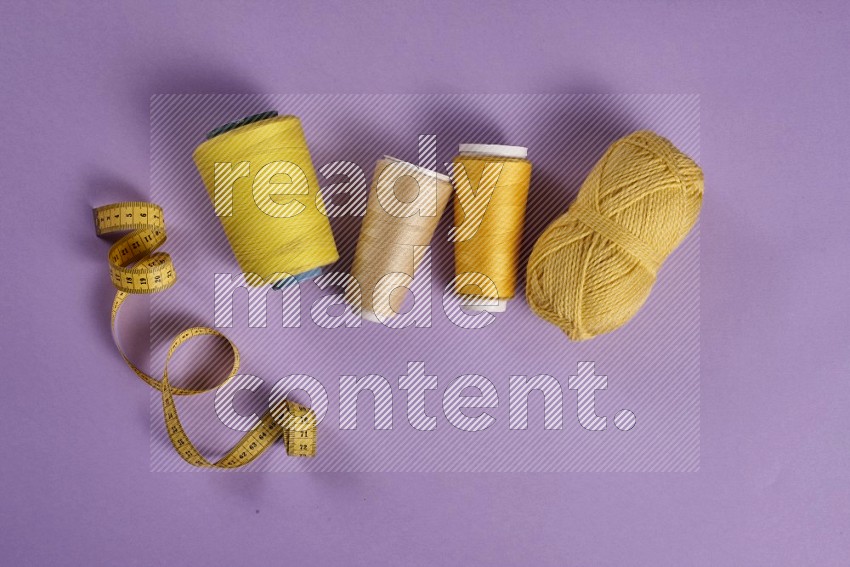 Yellow sewing supplies on purple background