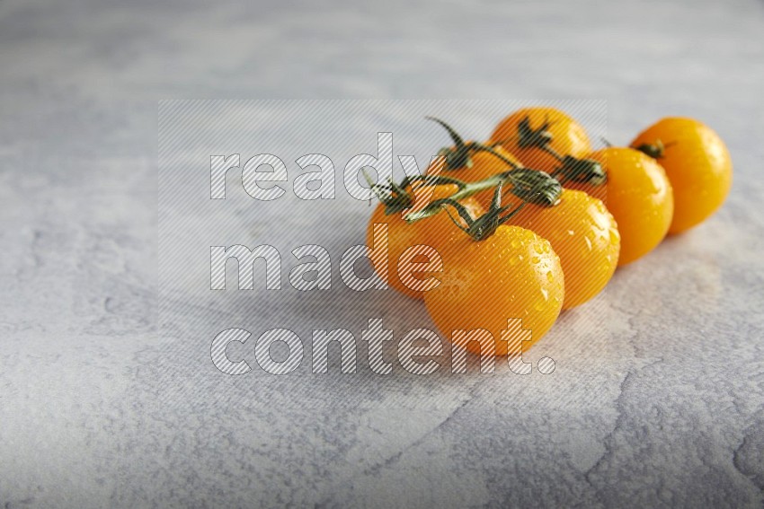Yellow cherry tomato vein on a light grey textured background 45 degree